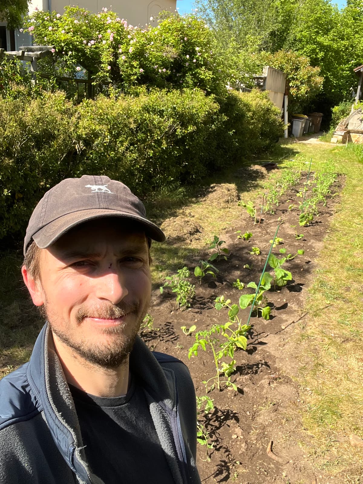 Léo en casquette devant une planche fraîchement plantée chez un client.
